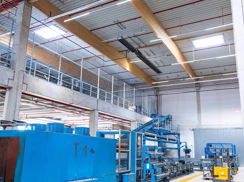 Schwank radiant heaters suspended under the roof of a warehouse
