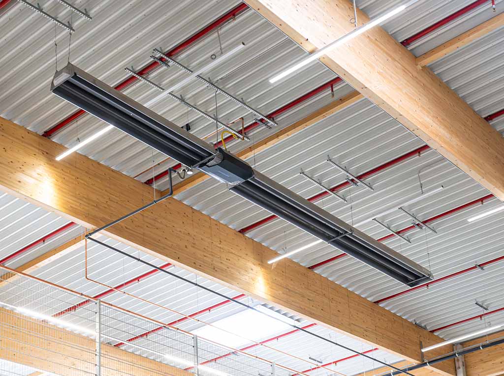 Schwank radiant heaters suspended under the roof of a warehouse